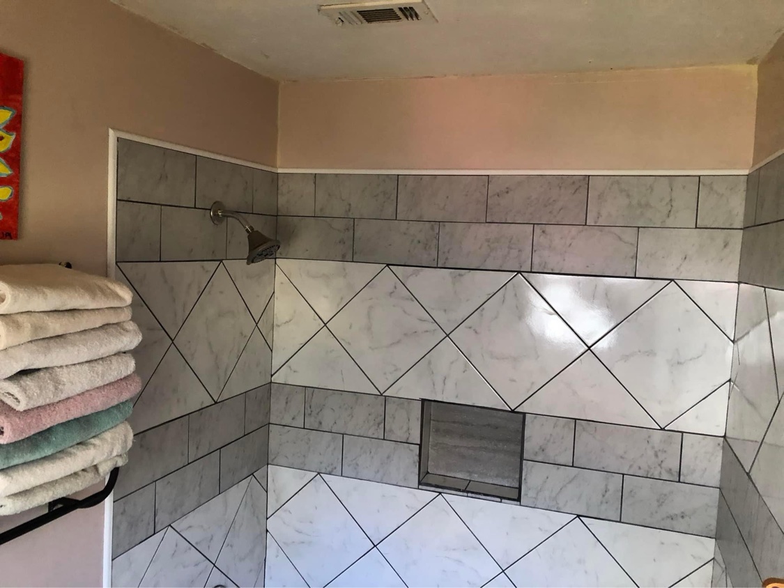 Remodeled bathroom with walk-in tile shower and stone-look porcelain