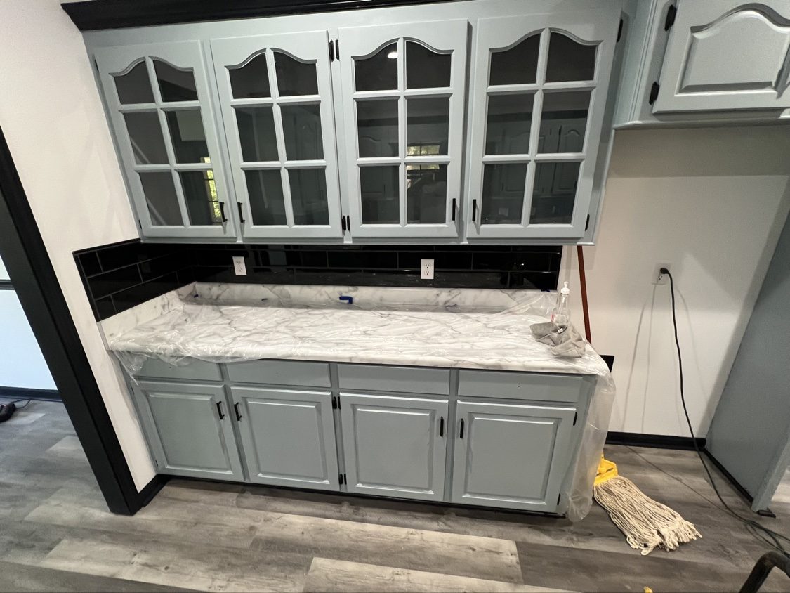 Finished kitchen with glass-front cabinets, marble-look counters and black backsplash