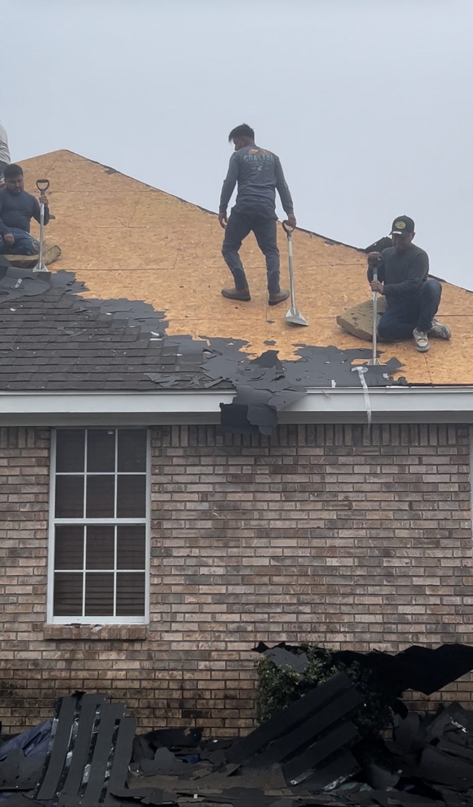 Crew stripping damaged shingles during a repair